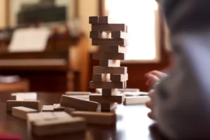 A person arranging wooden blocks on a table, showcasing creativity and problem-solving skills.