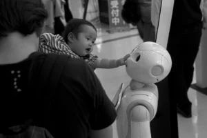 A baby curiously interacts with a robot in a store