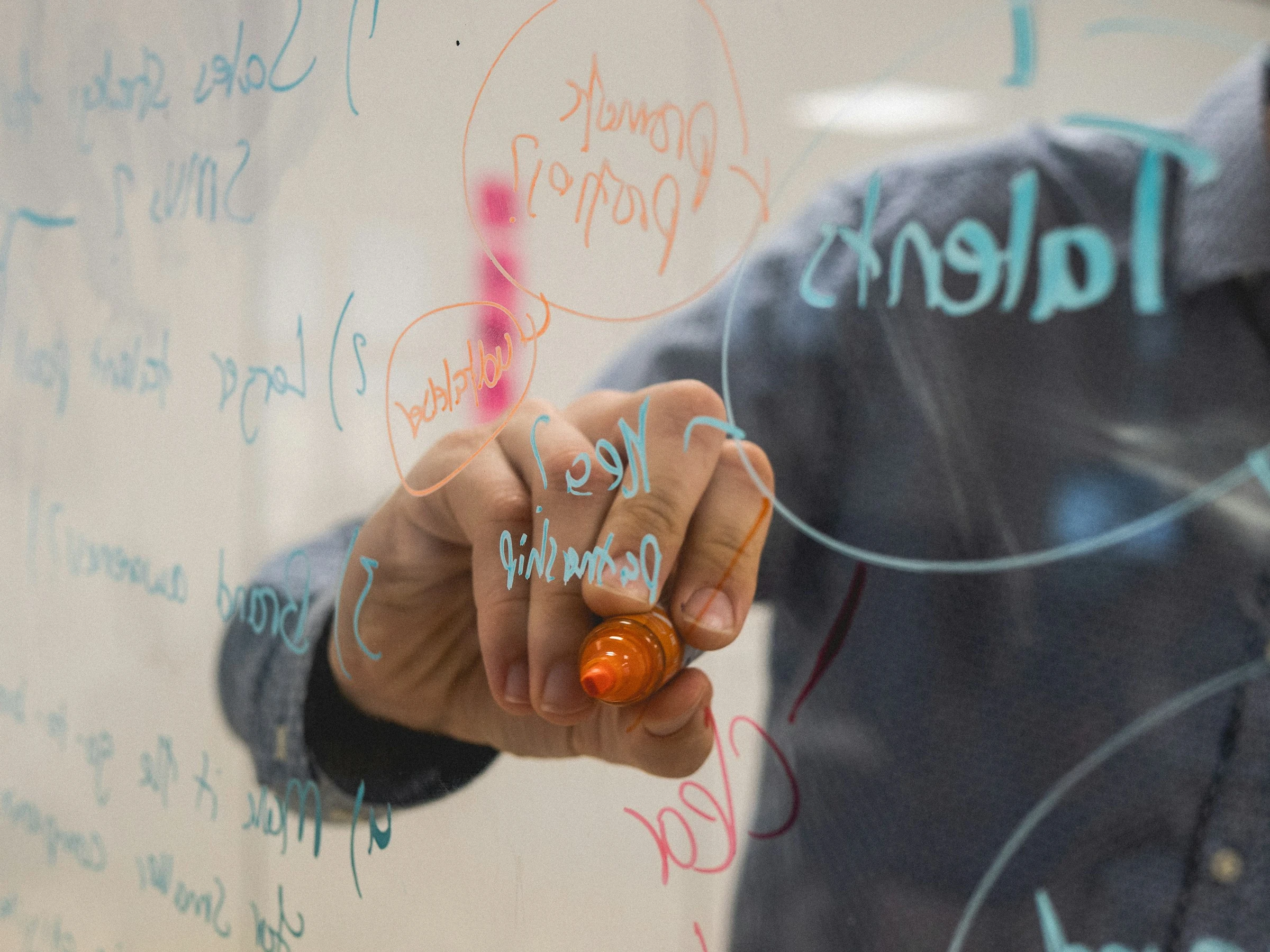 A man writing on a whiteboard, illustrating his ideas.