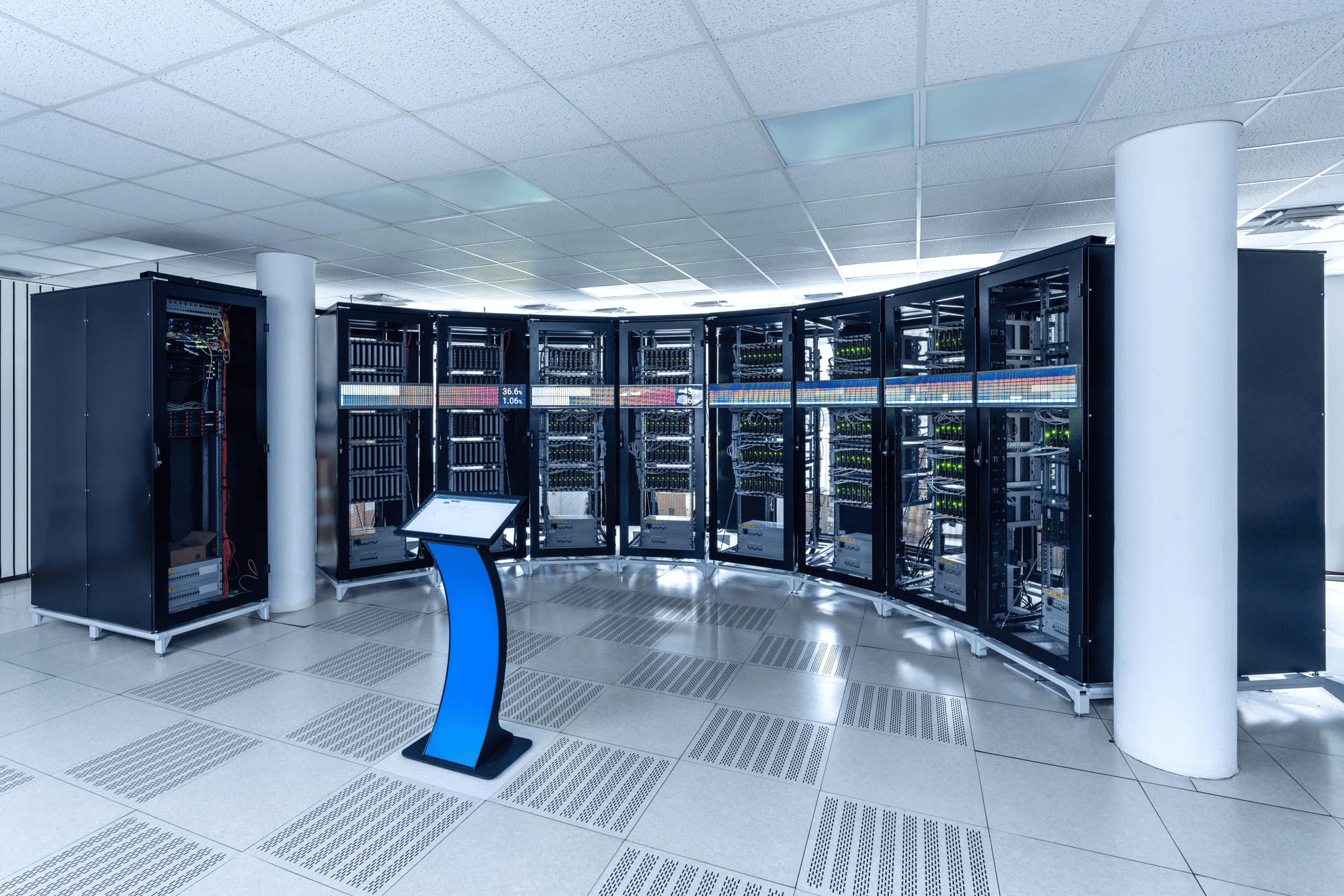 A modern server room with multiple server racks arranged in a curve and a blue touchscreen control panel in the center